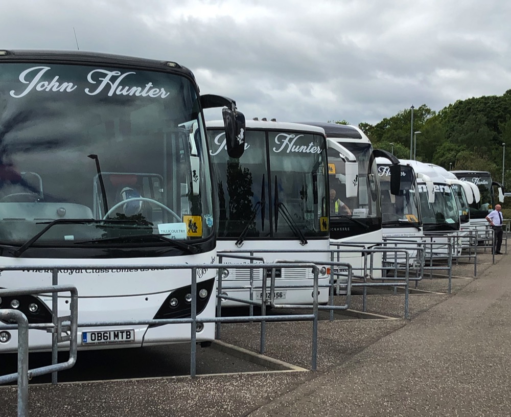 A number of Hunters coaches waiting to pick up in dedicated bays at a school